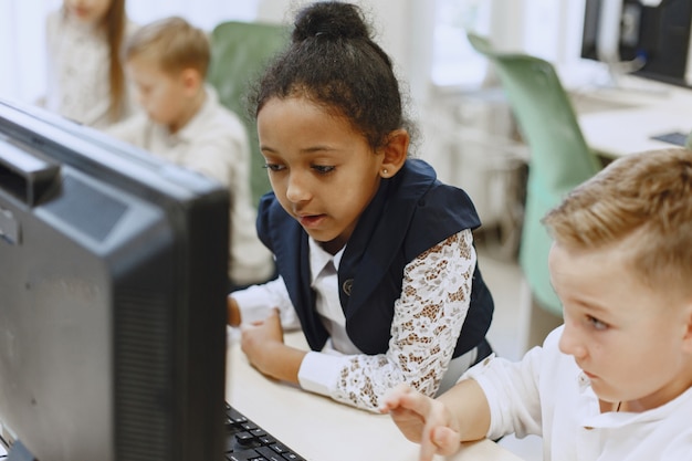 Free Photo guy and the girl are sitting at the table. african girl in computer science class. kids playing computer games.