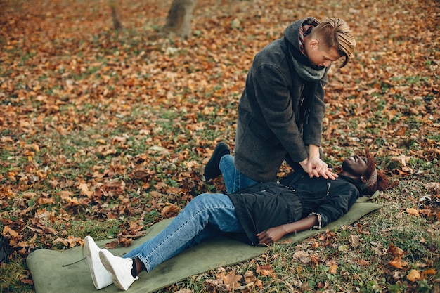 Free Photo guy help a woman. african girl is lying unconscious. providing first aid in the park.