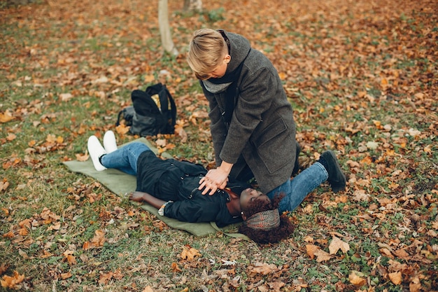 Free Photo guy help a woman. african girl is lying unconscious. providing first aid in the park.