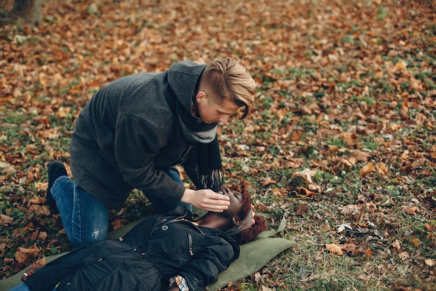 Free photo guy help a woman. afro girl is lying unconscious. providing first aid in the park