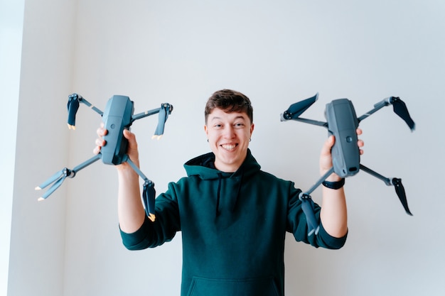 Free photo guy holds two quadrocopters against a wall