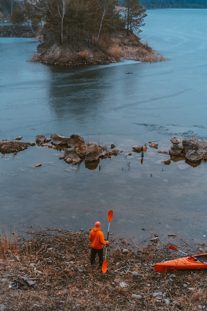 Free photo guy is standing at the frozen lake wih an oar