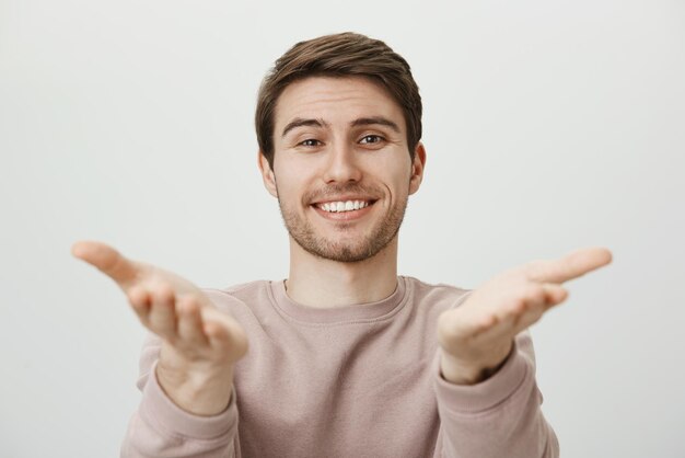 Guy is very happy to see you. Charming friendly caucasian brother directing with palms and looking with pleased and satisfied expression