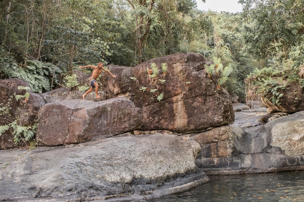 Free Photo the guy jumps from a stone into the water