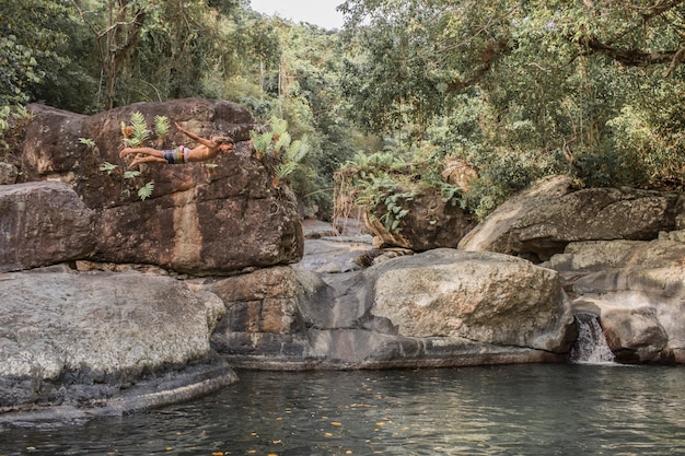 The guy jumps from a stone into the water