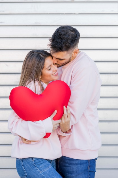 Guy kissing lady holding toy symbol of heart