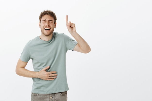 Free Photo guy likes woman with sense of humour. portrait of handsome funny male model in casual t-shirt, laughing out loud with closed eyes and broad smile