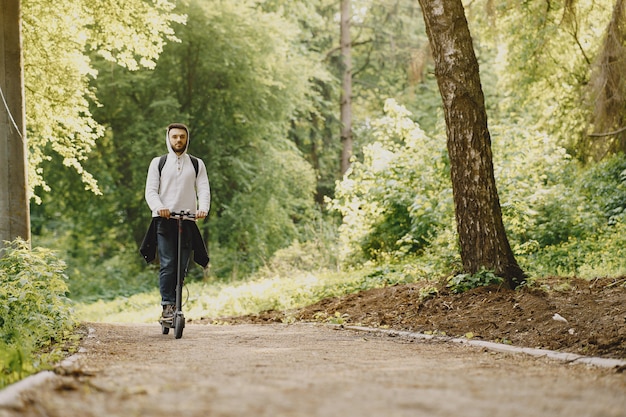 The guy rides an electric scooter in the summer Pforest