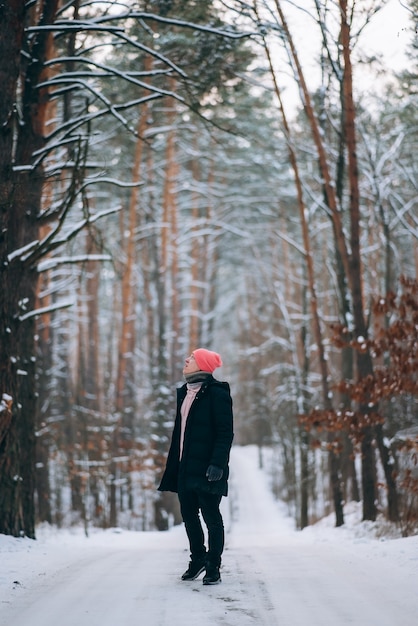 Guy standing on the road in the middle of the forest surrounded by snow