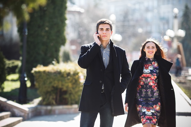 Free photo guy talking on the phone and walking with his girlfriend