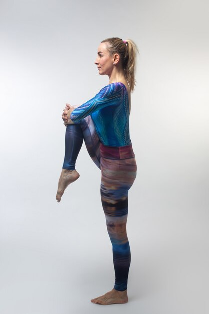 Gymnast in a multi-colored tights during streching