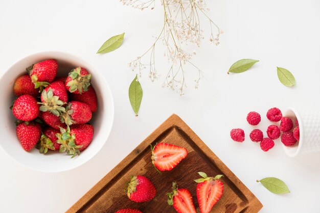 Gypsophila flowers and leaves with strawberries and raspberries isolated on white background