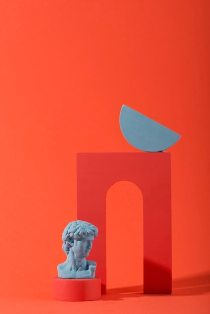 Free photo gypsum bust on coral background with geometric shapes