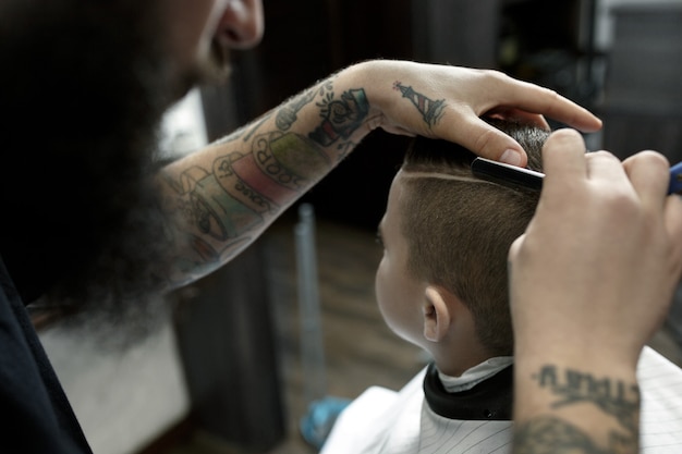 Hairdresser cutting little boy's hair