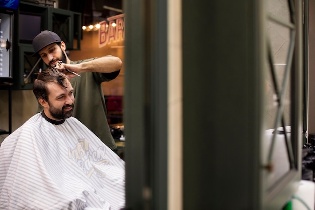 Free photo hairdresser cutting a man's hair at the barber shop