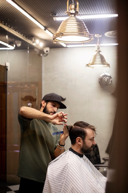 Free photo hairdresser cutting a man's hair at the barber shop