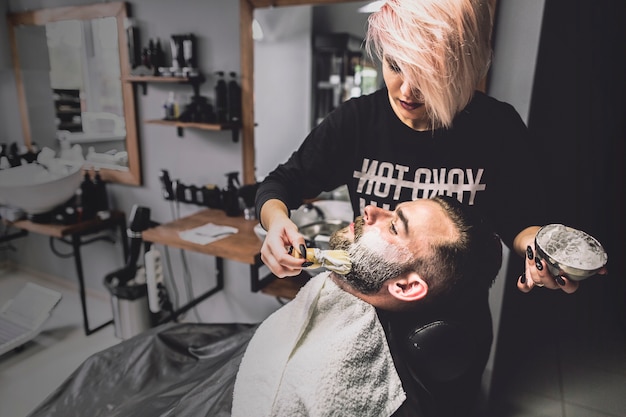 Free photo hairdresser putting foam on face of client