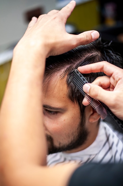 Hairstylist combing customer hair high view