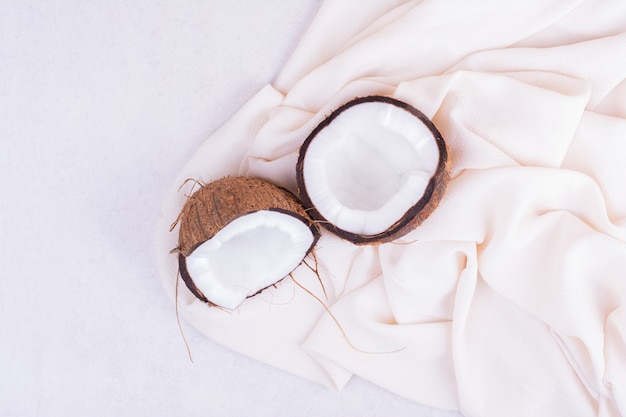 Free photo hairy coconut broken into half on white tablecloth.