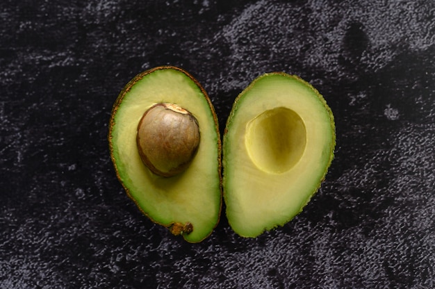 Free Photo half avocado on the black cement floor.