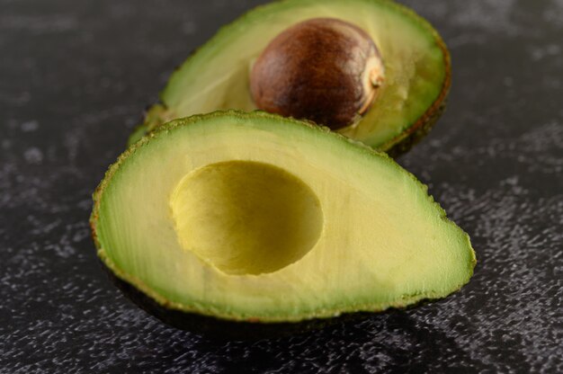 Half avocado on the black cement floor.