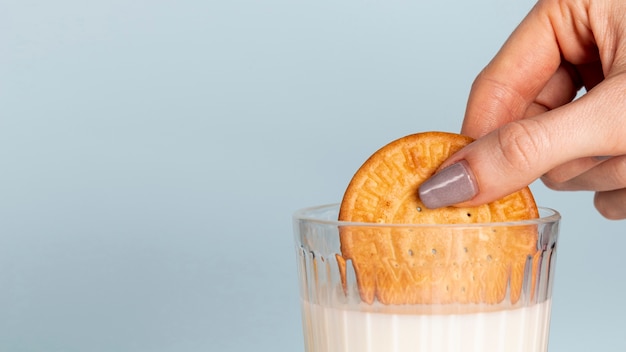 Half of biscuit dipped in a glass of milk and copy space background