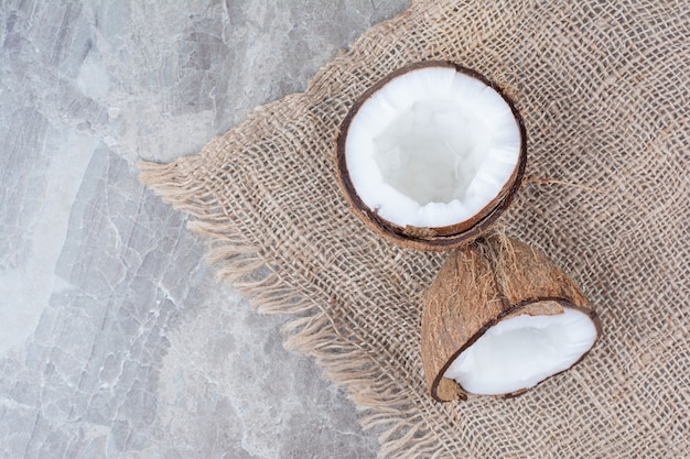 Half cut coconuts on stone surface with burlap. 