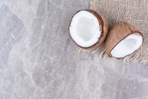 Half cut coconuts on stone surface with burlap. 