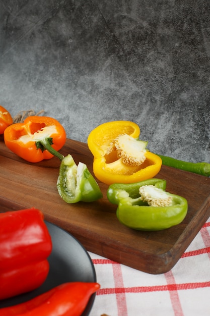 Free photo half cut colorful bell peppers on a wooden board.