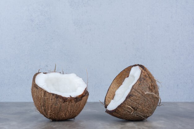 Half cut fresh coconuts on stone table. 