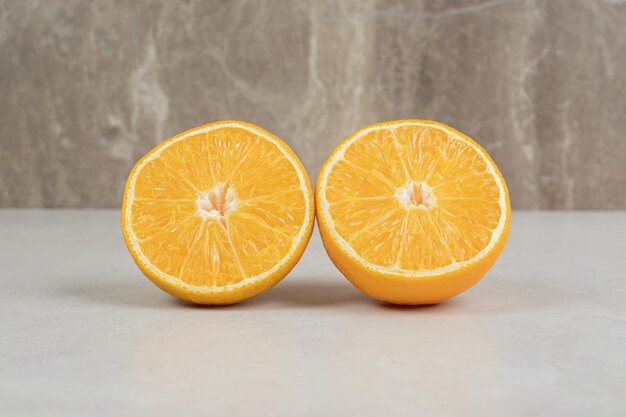 Half cut juicy oranges on gray table