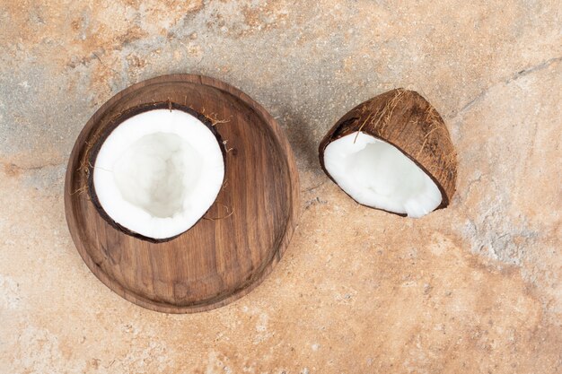 Half cut ripe coconuts on wooden plate.