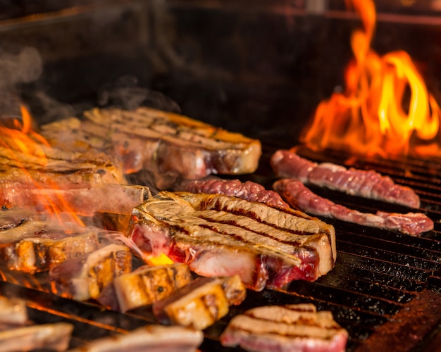 Free photo half grilled, half ready raw steaks on the grill