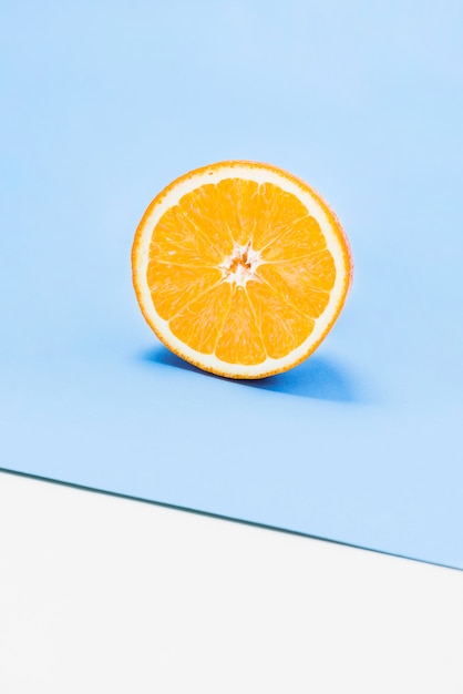 Free Photo half of juicy orange on white and blue background