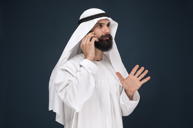 Half-length portrait of Arabian man on dark blue studio