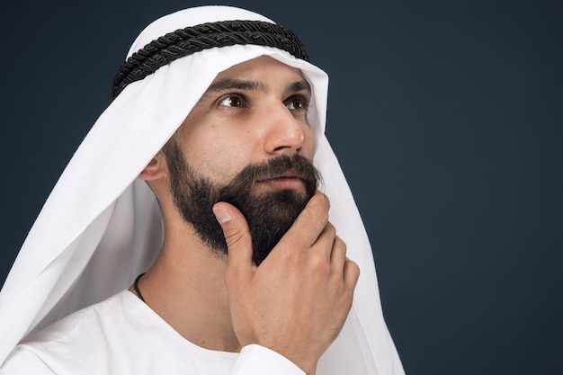 Half-length portrait of arabian saudi businessman on dark blue studio wall