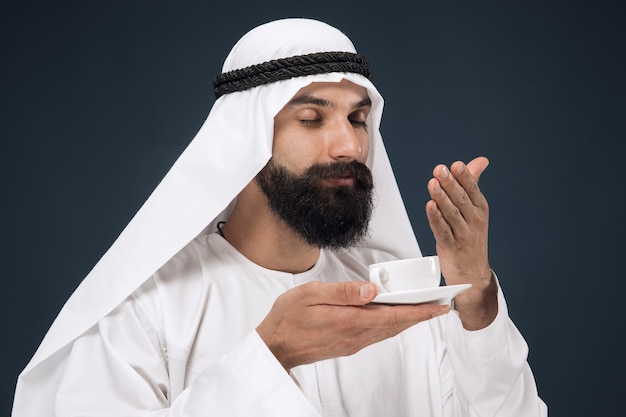 Half-length portrait of arabian saudi businessman on dark blue studio