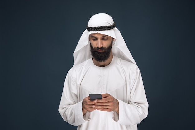 Free Photo half-length portrait of arabian saudi man on dark blue studio