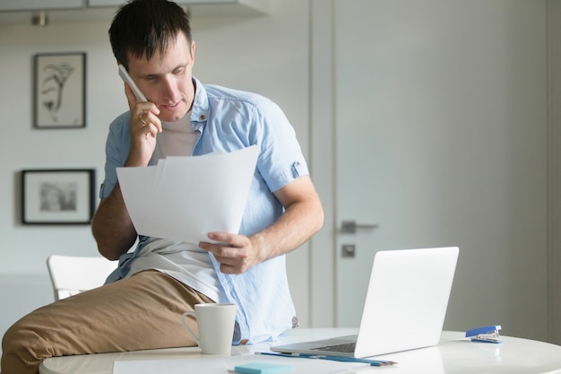 Half- length portrait of man, sitting at desk with phone