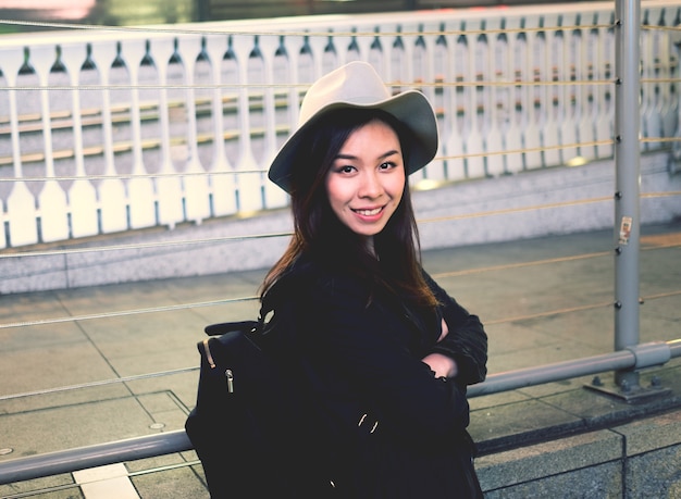 Free photo half length of young beautiful asiatic hipster woman in the city smiling looking in camera.