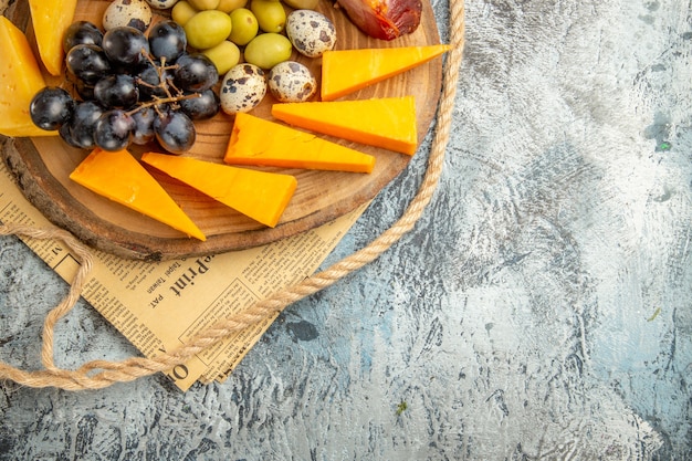 Free photo half shot of best snack with various fruits and foods on a wooden brown tray rope on an old newspaper