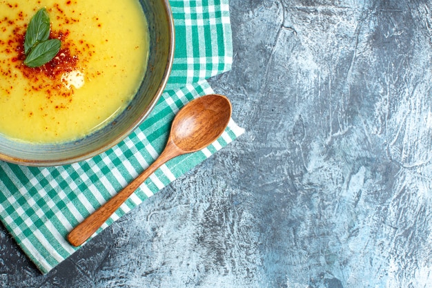 Free Photo half shot of a blue pot with tasty soup served with mint and wooden spoon on green stripped towel on blue background