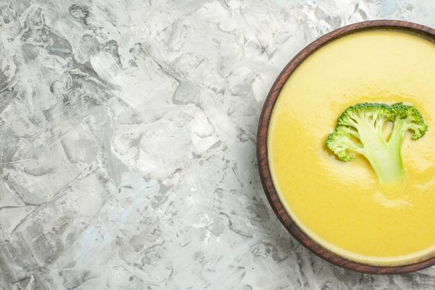 Free Photo half shot of cream of broccoli soup in a brown bowl on white table