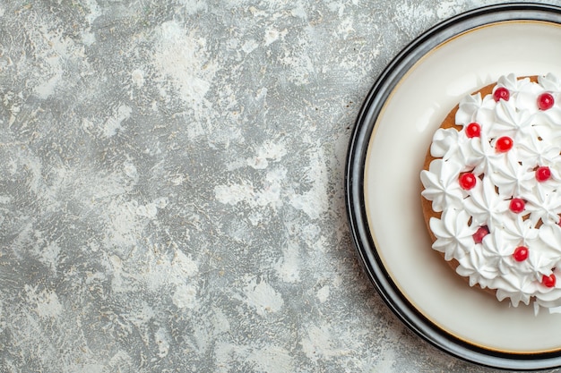 Half shot of delicious creamy cake decorated with fruits on the left side on ice background