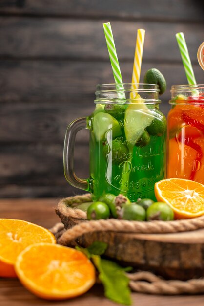 Half shot of delicious fresh juices and fruits on a wooden tray on a brown background