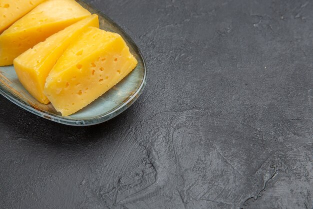 Half shot of delicious yellow sliced chees on a blue plate on the right side on black background