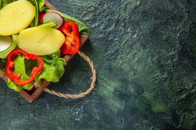 Half shot of fresh chopped vegetables on a wooden tray on the right side on mix colors surface with free space