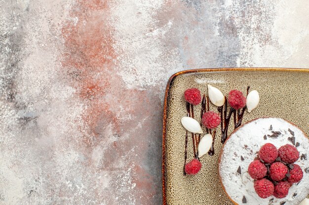 Half shot of freshly baked cake with raspberries for babieson a white tray on mixed color table