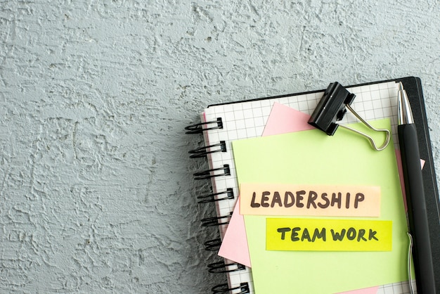 Free photo half shot of leadership teamwork on coloured envelopes on spiral notebook and book on gray sand background