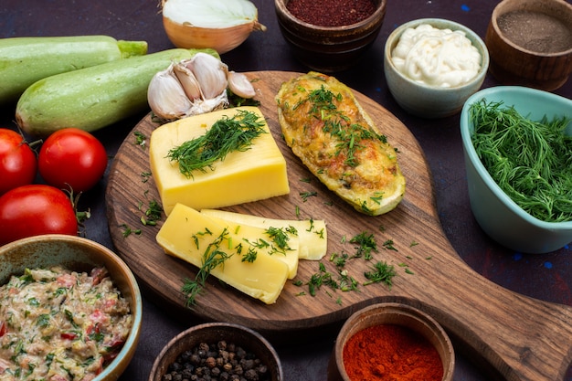 Free photo half-top close view baked squashes with greens cheese seasonings meat and fresh vegetables on dark desk.